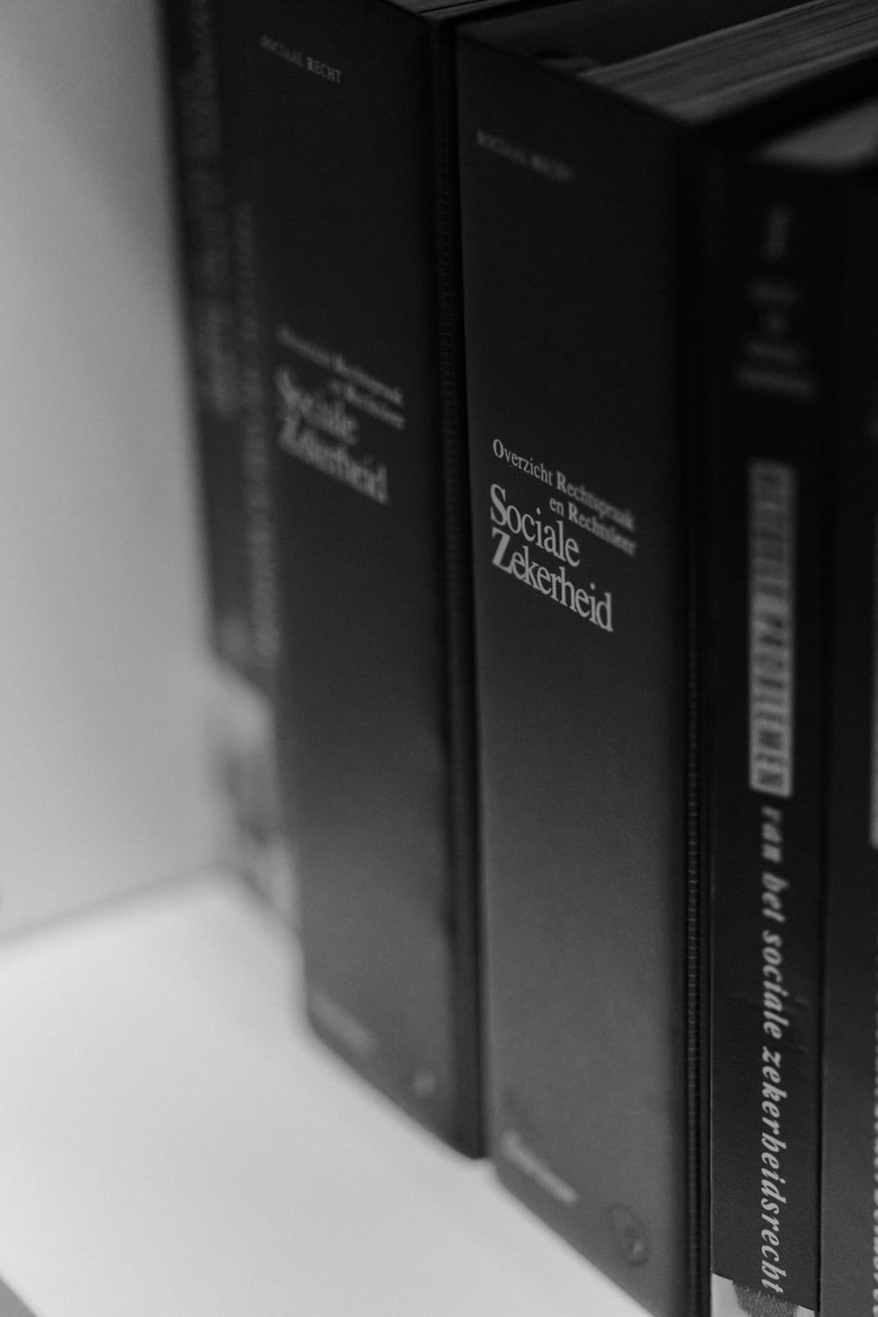 Een close-up van stapel boeken over sociaal recht en sociale zekerheid in zwart-wit.